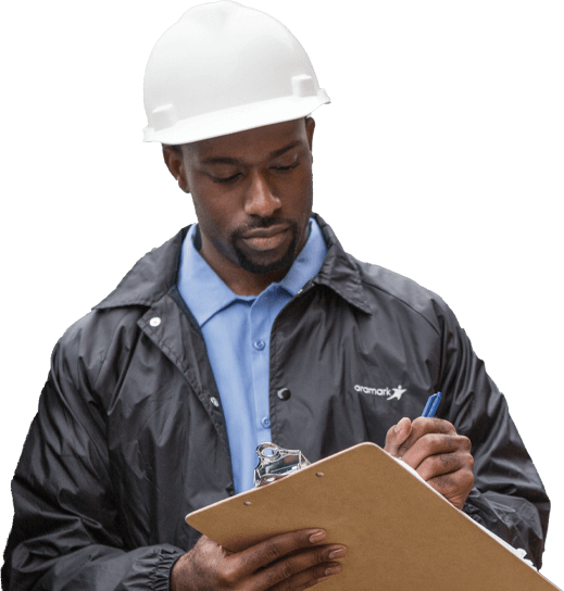 aramark employee wearing a hard hat and writing on a clipboard
